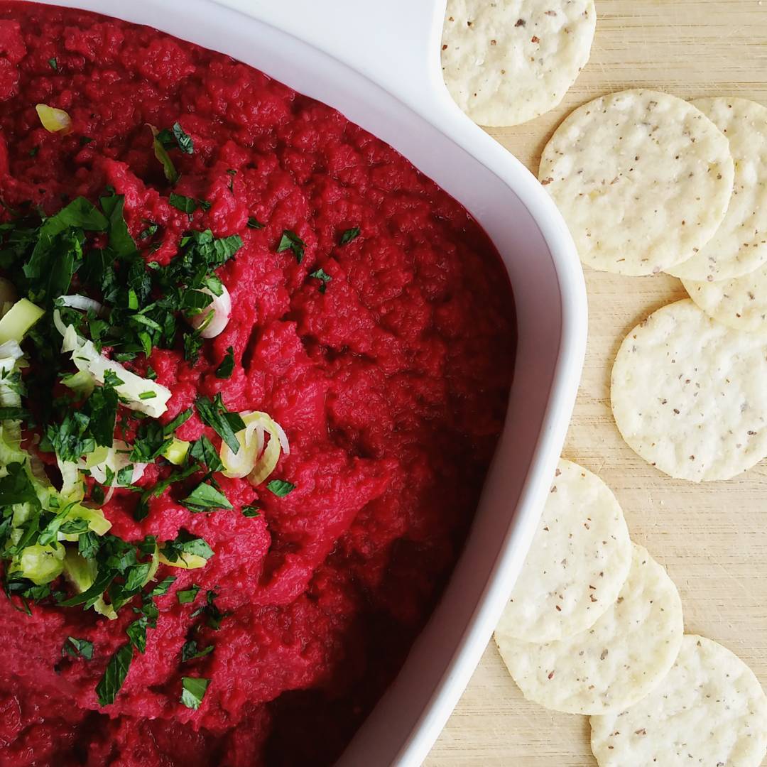 bowl of roasted beet hummus with a side of crackers